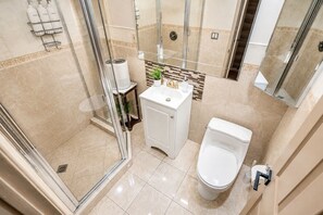 Ein modernes Badezimmer mit einer gläsernen Duschkabine, einem weißen Waschbecken mit Spiegel und einer Toilette.