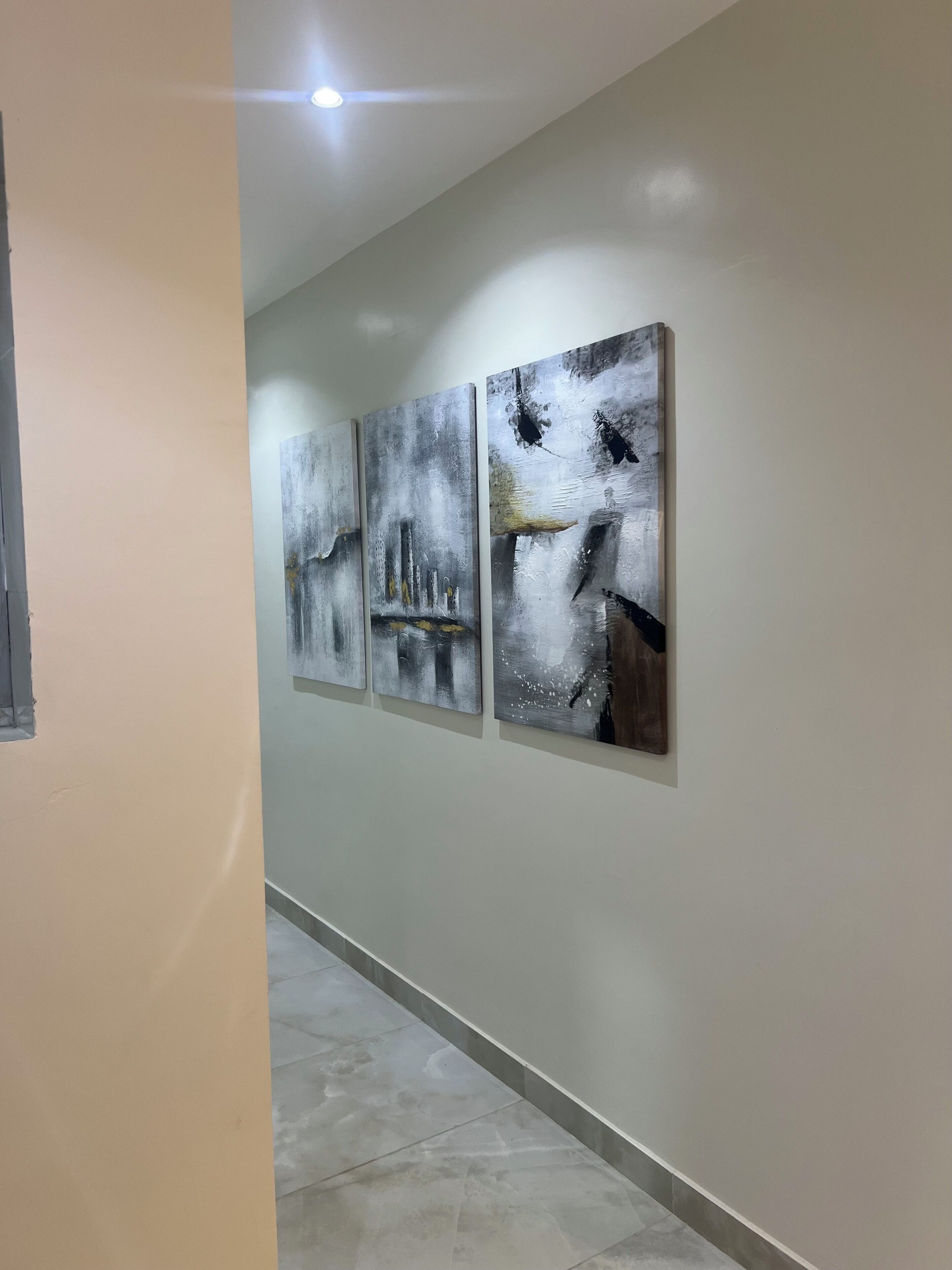 Un couloir orné de trois tableaux abstraits.