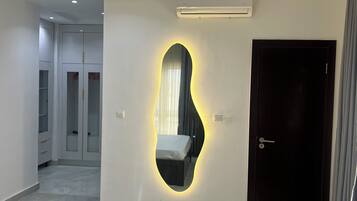 Une chambre à coucher moderne avec un lit, un miroir fixé au mur et une porte.