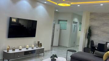 Un salon moderne comprenant un téléviseur à écran plat, un ensemble de canapés, une table basse et une console agrémentée d’objets décoratifs.
