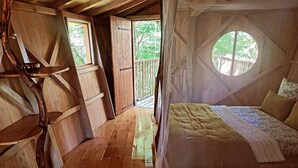 A wooden cabin bedroom with a bed, a window, and a balcony. - Cabane Isabelle - Ile aux Cabanes 2 pers (STE COLOMBE)
