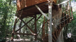 A wooden treehouse with a platform and stairs, surrounded by trees. - Cabane Isabelle - Ile aux Cabanes 2 pers (STE COLOMBE)