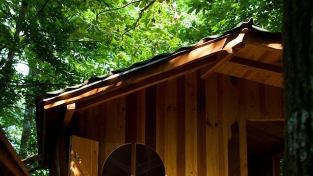 A wooden cabin with a deck, two white metal chairs, and a table. - Cabane Isabelle - Ile aux Cabanes 2 pers (STE COLOMBE)