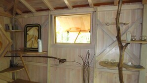 A rustic wooden room with a wooden floor, a window with a view, and shelves with various items. - Cabane Isabelle - Ile aux Cabanes 2 pers (STE COLOMBE)