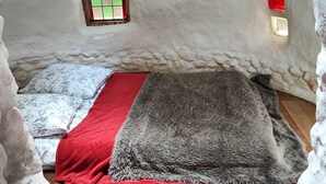 A cozy, single-bed room with a red and grey blanket, a small window with green and white panes, and a red light switch on the wall. - Ker-terre de Flo - 2 pers (STE COLOMBE)