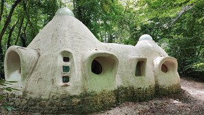 A unique treehouse structure with multiple openings and a natural forest setting. - Ker-terre de Flo - 2 pers (STE COLOMBE)