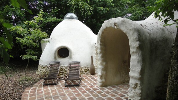 A rustic outdoor seating area with two wooden lounge chairs and a brick-paved circular patio. - Ker-terre de Flo - 2 pers (STE COLOMBE)