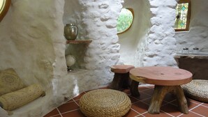 A rustic interior with a stone wall, a round woven stool, a wooden table, and a globe on a shelf. - Ker-terre de Flo - 2 pers (STE COLOMBE)