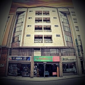 A multi-story building with various shops on the ground floor, including a shoe store and a restaurant. - Hotel Santa Isabel II (Ipiales)