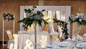 A banquet hall with round tables set for a formal event, featuring white tablecloths, gold-rimmed plates, and floral centerpieces. - Hotel Santa Isabel II (Ipiales)