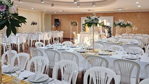 A banquet hall with round tables, white chairs, and floral centerpieces. - Hotel Santa Isabel II (Ipiales)