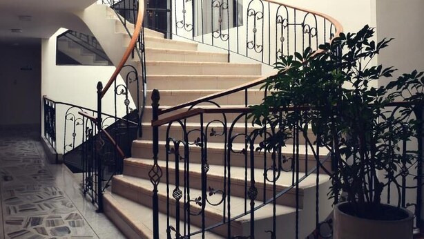 A staircase with ornate black railings and beige steps leading to an upper floor. - Hotel Santa Isabel II (Ipiales)