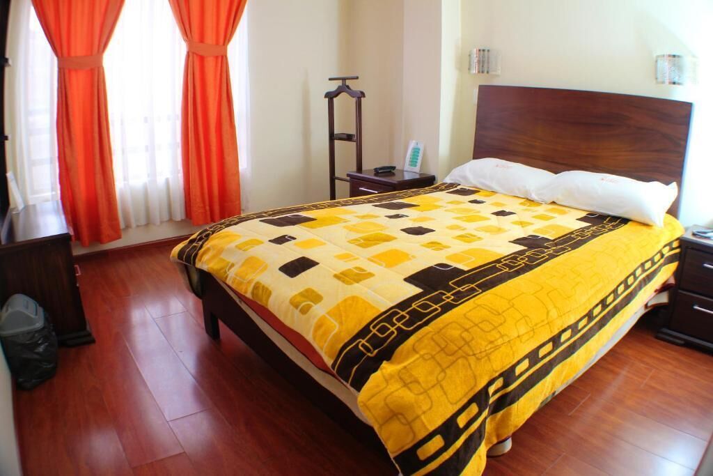 Quarto de hotel bem arrumado, com uma cama, cabeceira de madeira e mesa de cabeceira.