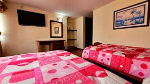 A hotel room with two beds, a desk, a chair, a television, and a framed picture on the wall. - Hotel Santa Isabel II (Ipiales)