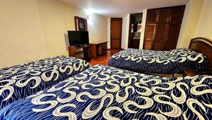 A hotel room with two beds, a desk, a television, and a wardrobe. - Hotel Santa Isabel II (Ipiales)