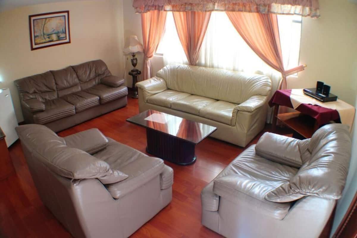 Ein Wohnzimmer mit einem braunen Ledersofa, einem weißen Ledersofa und einem Glastisch.