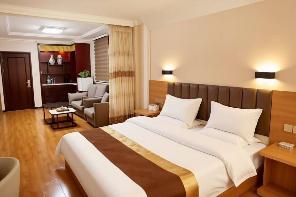Een hotelkamer met een groot bed, een bureau, een stoel, een zithoek en een kitchenette.