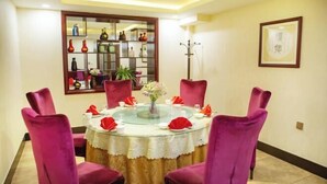 Un coin repas avec une table ronde en verre, des chaises rouges et un vase décoratif.