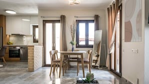 A modern kitchen with a built-in oven and a dining area with a wooden table and chairs. - Niriides Villas | Nymfe | Villa 2-bedrooms with private pool (Hersonissos)