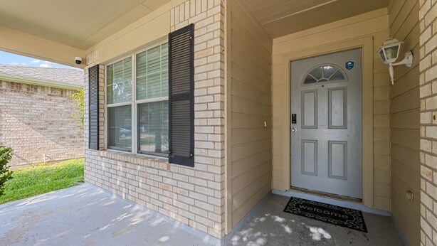 A house with a front door, a covered porch, and a brick exterior.