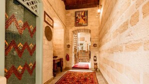 Un pasillo con alfombra estampada, una escalera y un cuadro en la pared.