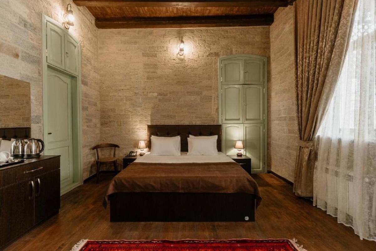 Una camera da letto con testiera in legno, un letto con lenzuola bianche, un comodino con una lampada e un armadio con ante verde chiaro.