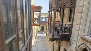 Un estrecho callejón empedrado entre edificios con balcones de madera y ventanas amplias.