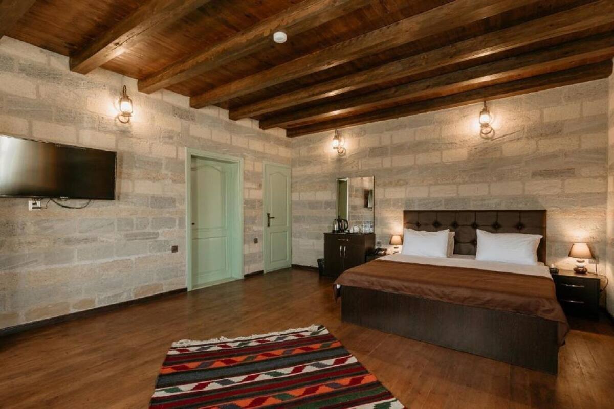 Una camera da letto con un letto grande, una TV a schermo piatto montata a parete e un muro in pietra.