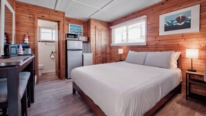 Een kamer met een bed, bureau, magnetron en koelkast.
