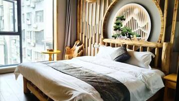 Een bed met een houten hoofdbord, een ronde decoratie aan de muur en een klein tafeltje ernaast.