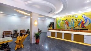 A hotel reception area with a modern design, featuring a reception desk, seating area with chairs, and a large wall mural. - Home Inn Huayi Hotel (Wudangshan Jingqu Rukou Road) (Danjiangkou)