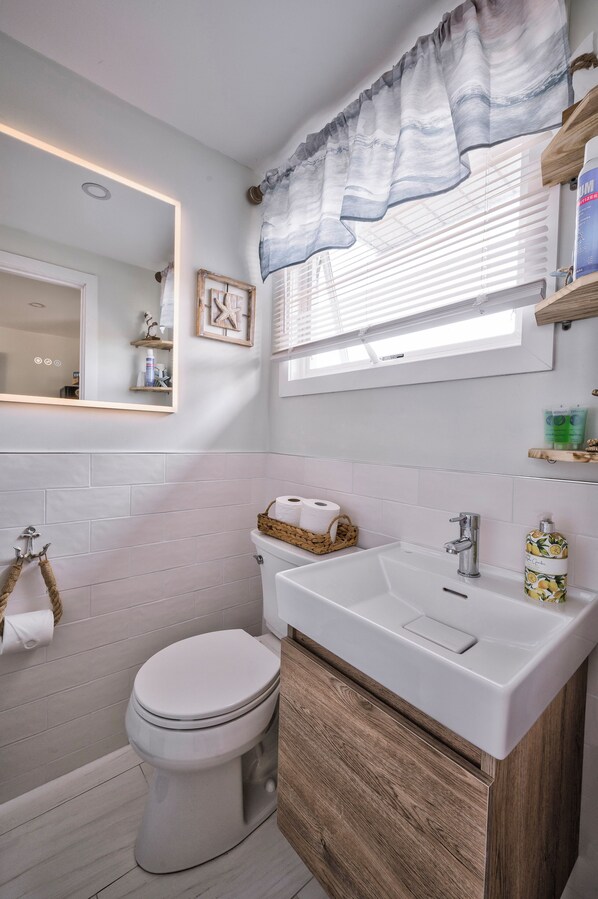 A modern bathroom with a toilet, sink, and vanity.