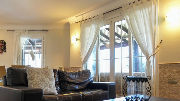 Een woonkamer met een leren bank, een bijzettafeltje en een decoratieve glazen vaas.