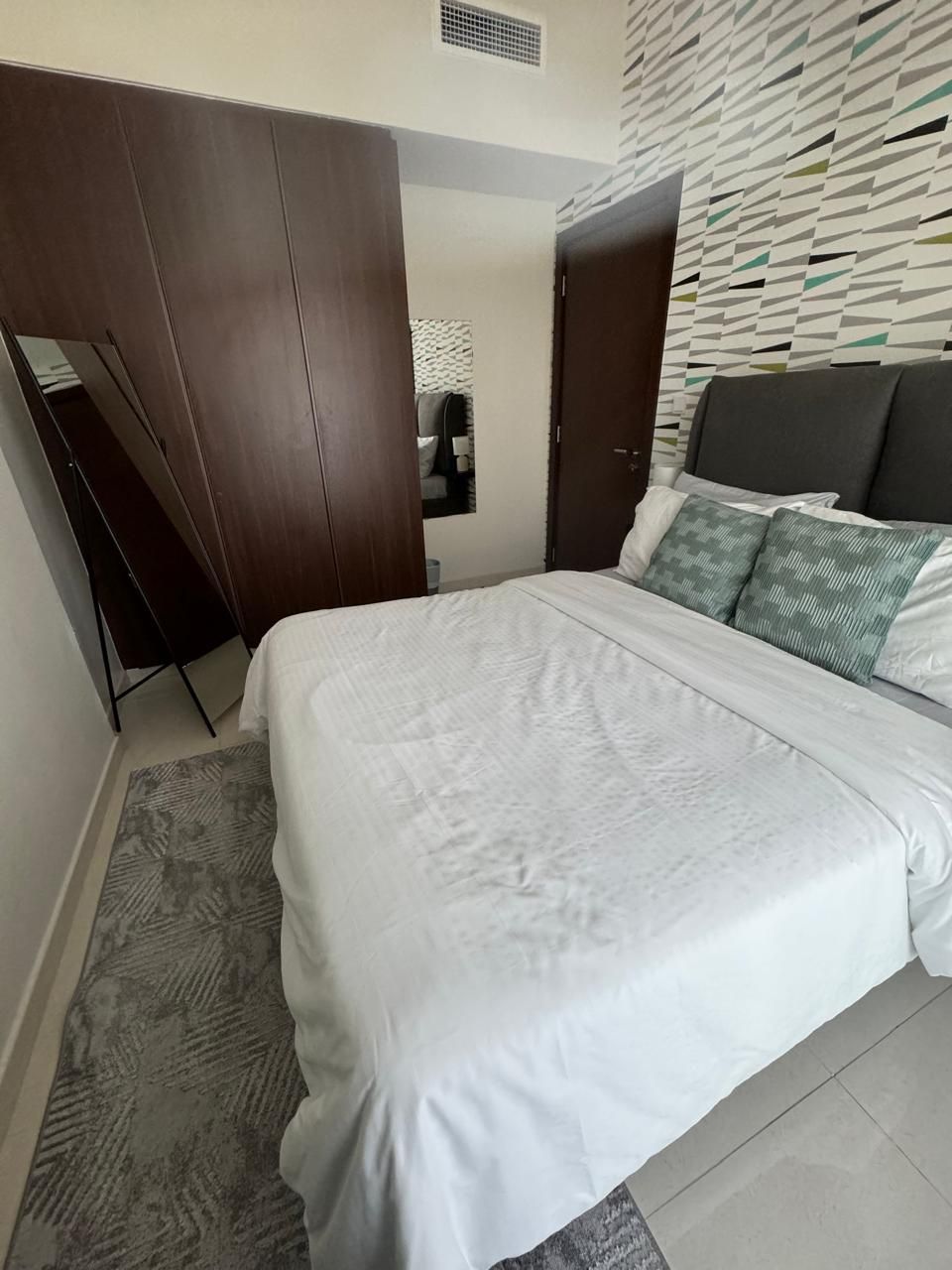 Un dormitorio con una cama, un armario y una pared con diseño.