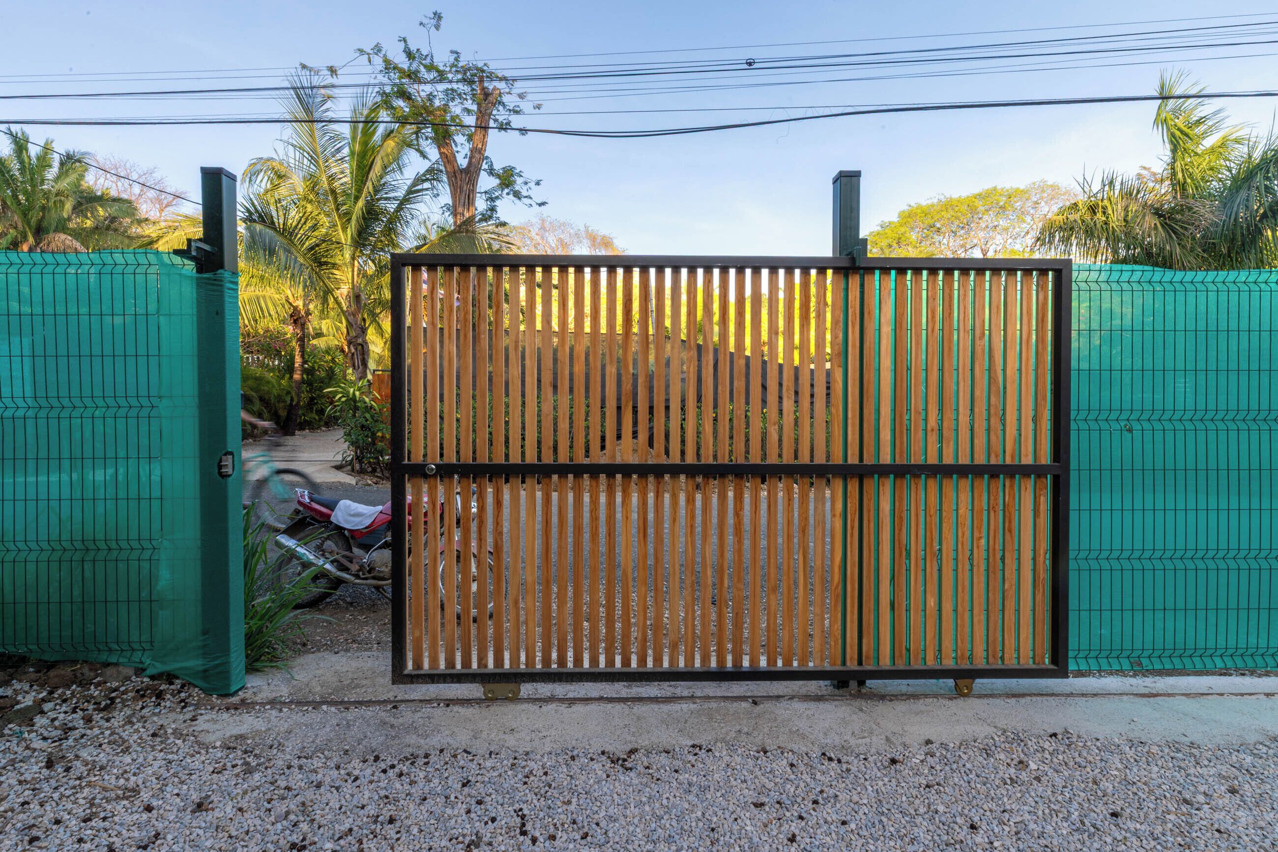 A gated entrance with a metal gate and a green fence.