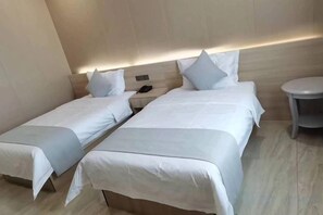 A hotel room with two single beds, a bedside table with a phone, and a round table. - Holiday Inn (Yanqi)