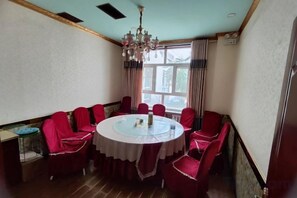 A dining room with a round table, red upholstered chairs, a chandelier, and a window with curtains. - Holiday Inn (Yanqi)