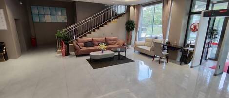 A spacious living area with a sofa set, a coffee table, and a staircase leading to an upper floor.