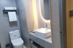 A bathroom with a toilet, sink, and mirror.