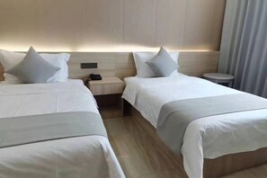 A hotel room with two beds, a bedside table with a phone, and a small stool.
