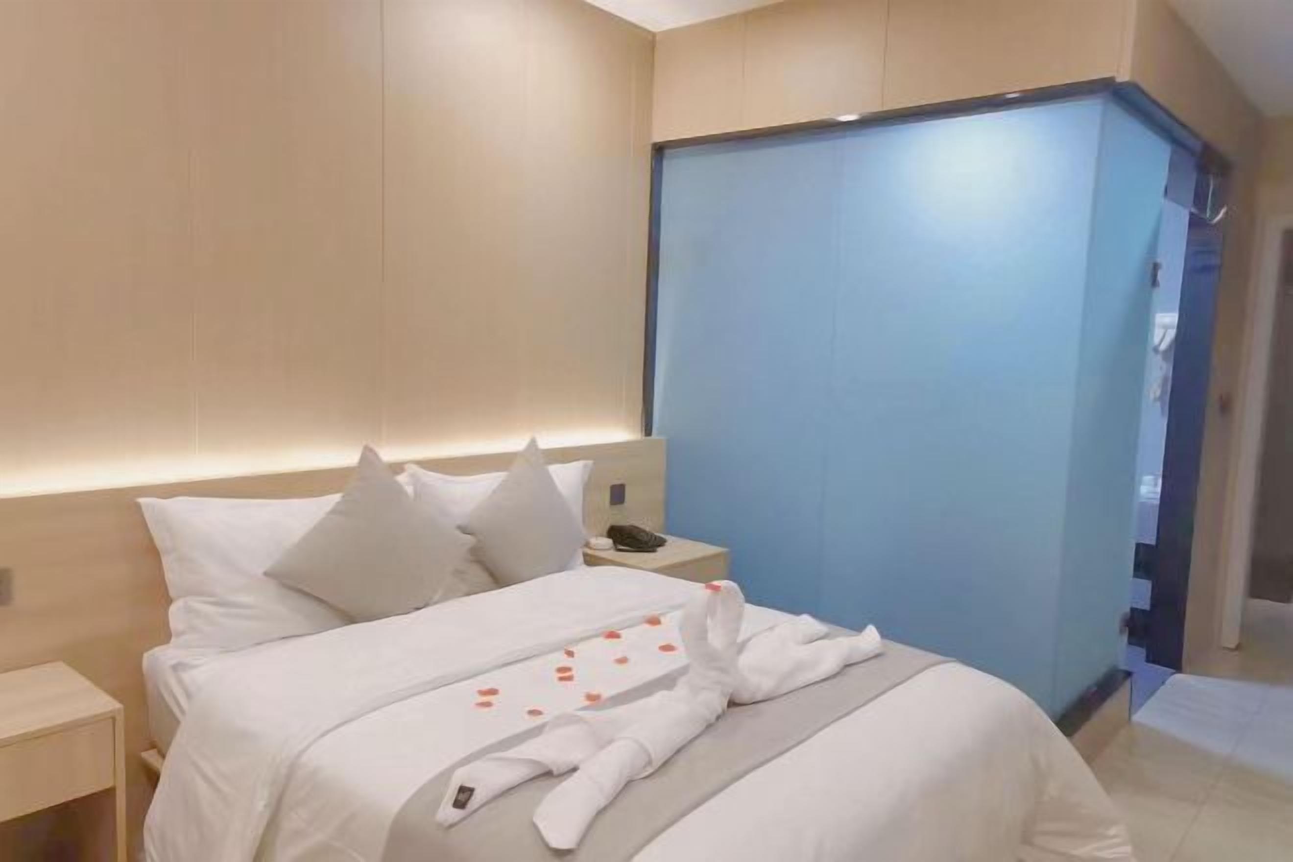 Quarto de hotel moderno com cama, mesa de cabeceira e uma porta deslizante azul.