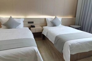 A hotel room with two beds, a bedside table, and a small round table. - Holiday Inn (Yanqi)