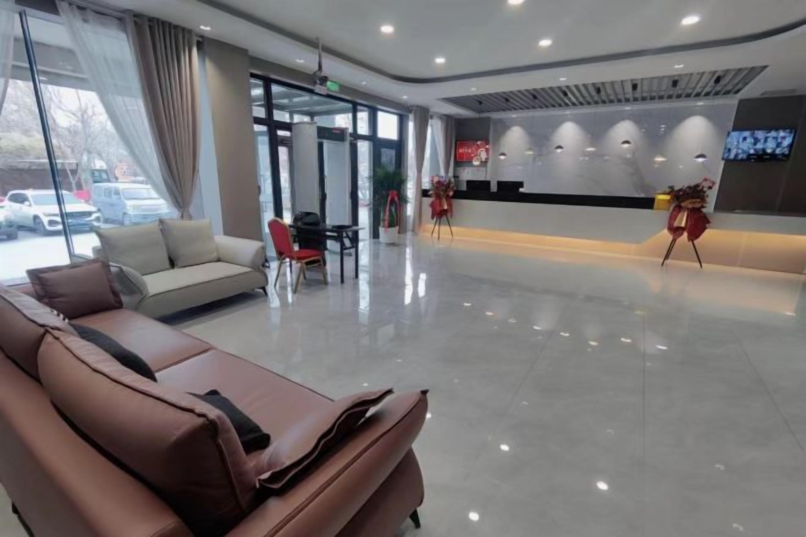 Um hall de hotel moderno com área de estar, balcão de recepção e uma janela grande.