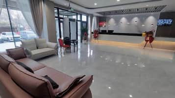 Um hall de hotel moderno com área de estar, balcão de recepção e uma janela grande.