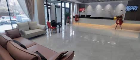 Un vestíbulo de hotel con una recepción, un sofá y una zona de estar.