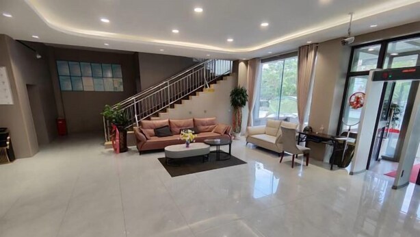 A spacious lobby with a modern design, featuring a staircase, a seating area with sofas and a coffee table, and a large window providing natural light. - Holiday Inn (Yanqi)