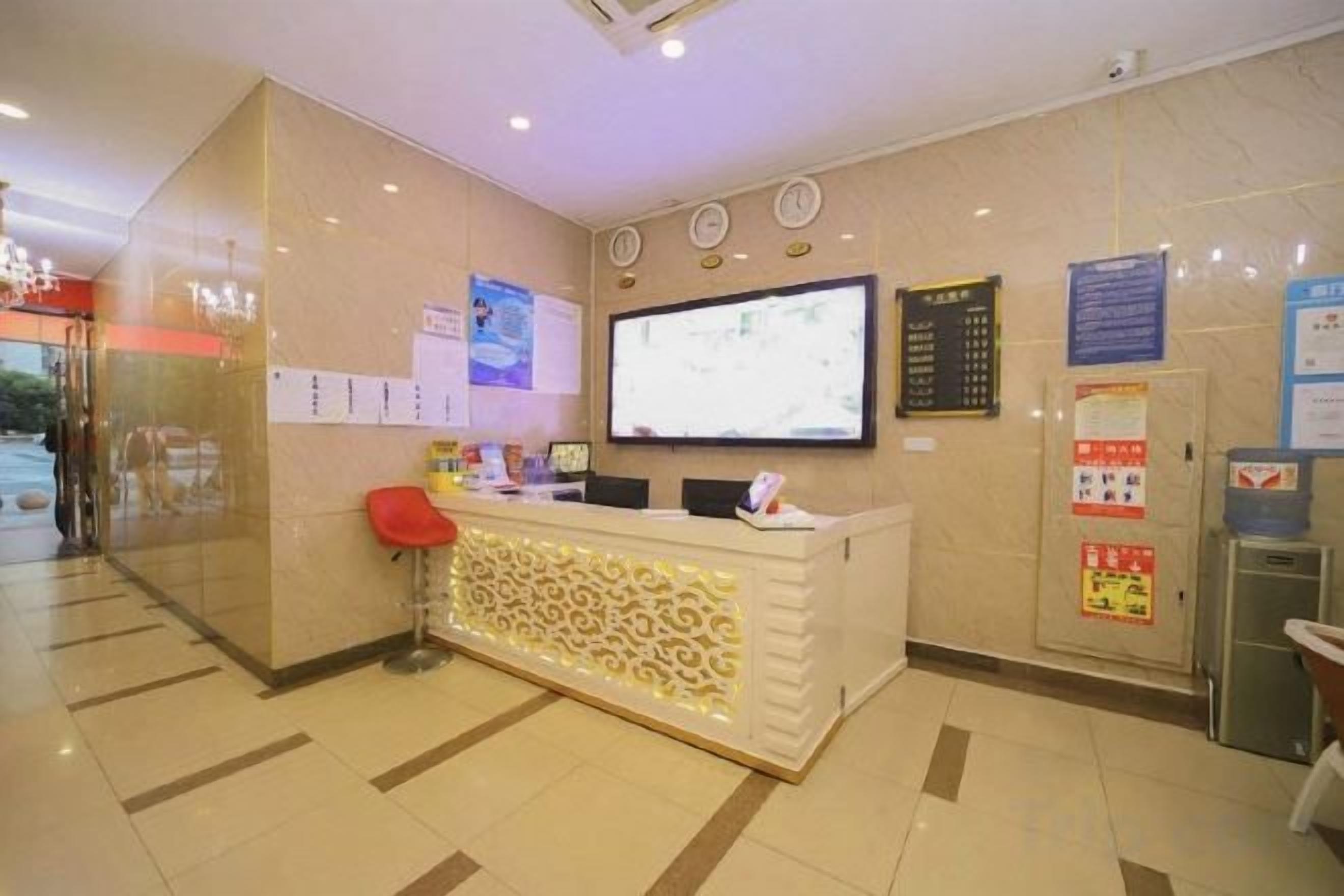 A reception area with a counter, a television screen, and a wall-mounted information board.