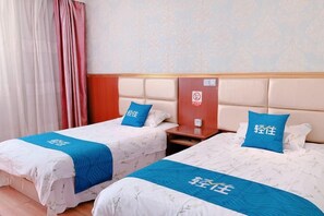 Two twin beds with blue headboards and matching pillows, a wooden nightstand, and a patterned wall. - Huchen Fashion Hotel (Shanghai)