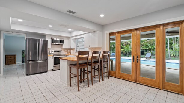A modern kitchen with a central island, stainless steel appliances, and a view of a swimming pool.