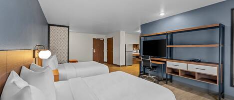 A modern hotel room with a large bed, a desk with a chair, a TV, and a wardrobe.
